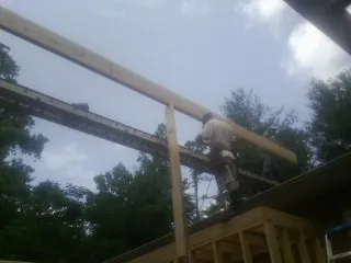 Carpenter setting a ridge beam over a new addition frame — Ice Dam Removal by Roofing Brothers in Ennice