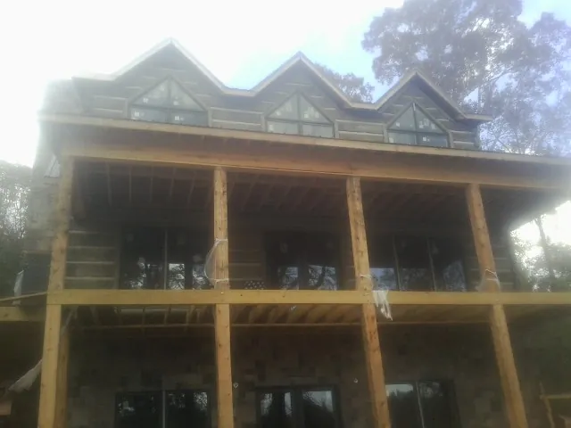 Dormers and porch framing on a large log home under construction — Roof Coating work by our crew in Ennice