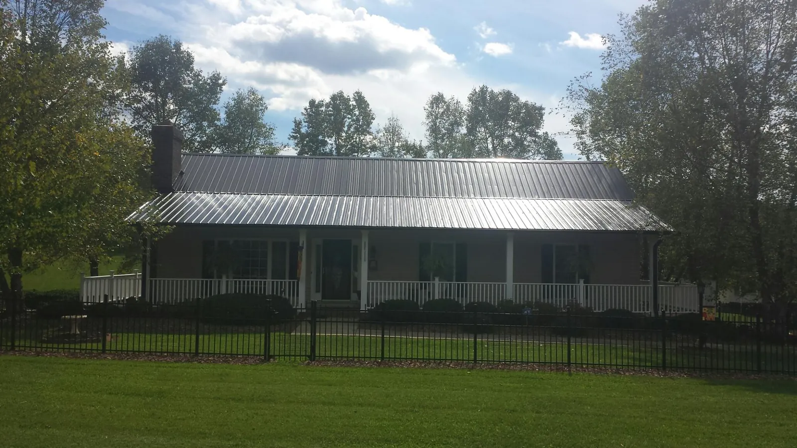 Gray metal roof on a brick ranch with a full width front porch — Gutter Guard Installation work by our crew in Ennice
