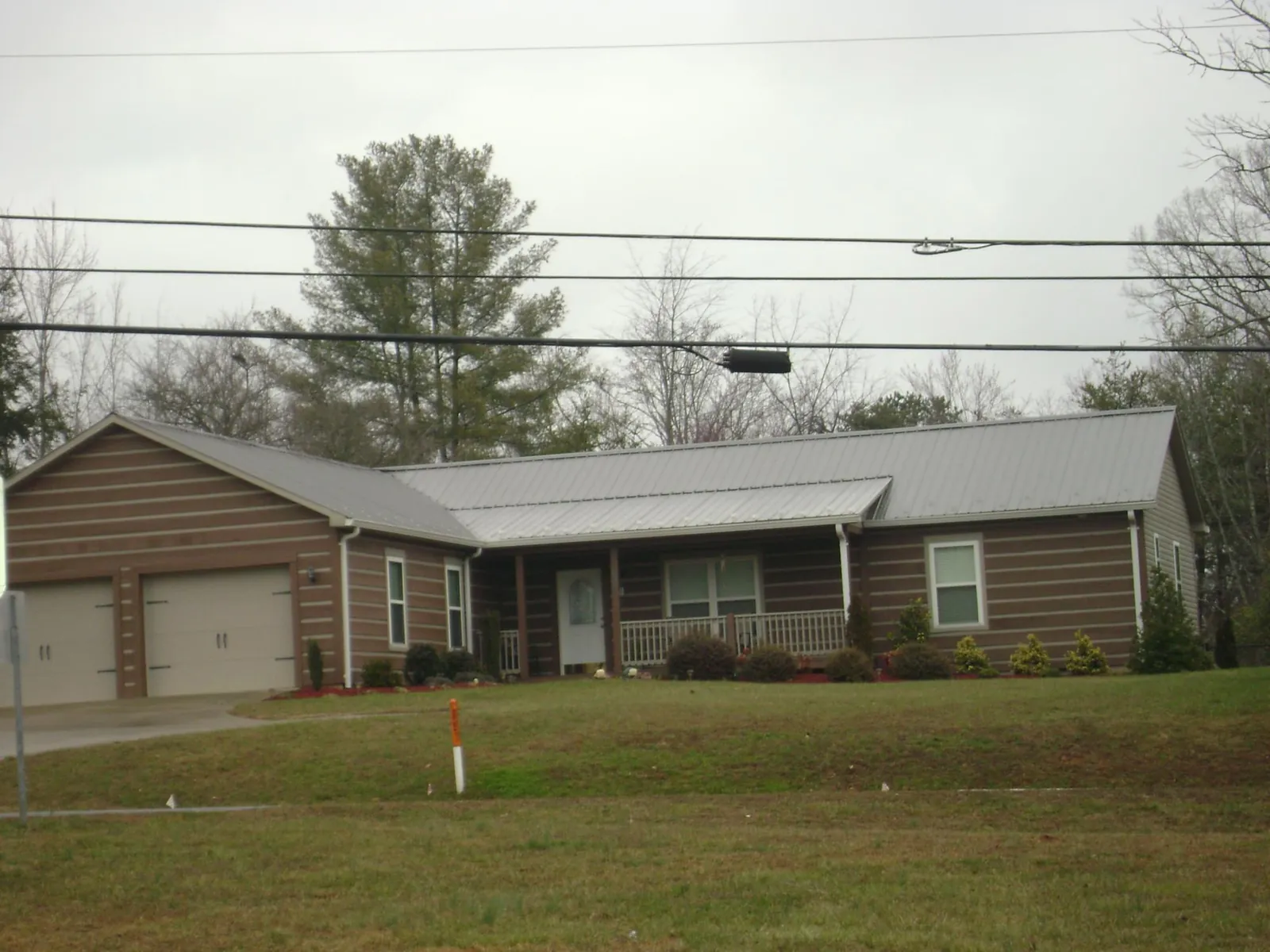 Gray metal roof on a log sided ranch home with a front porch in Ennice