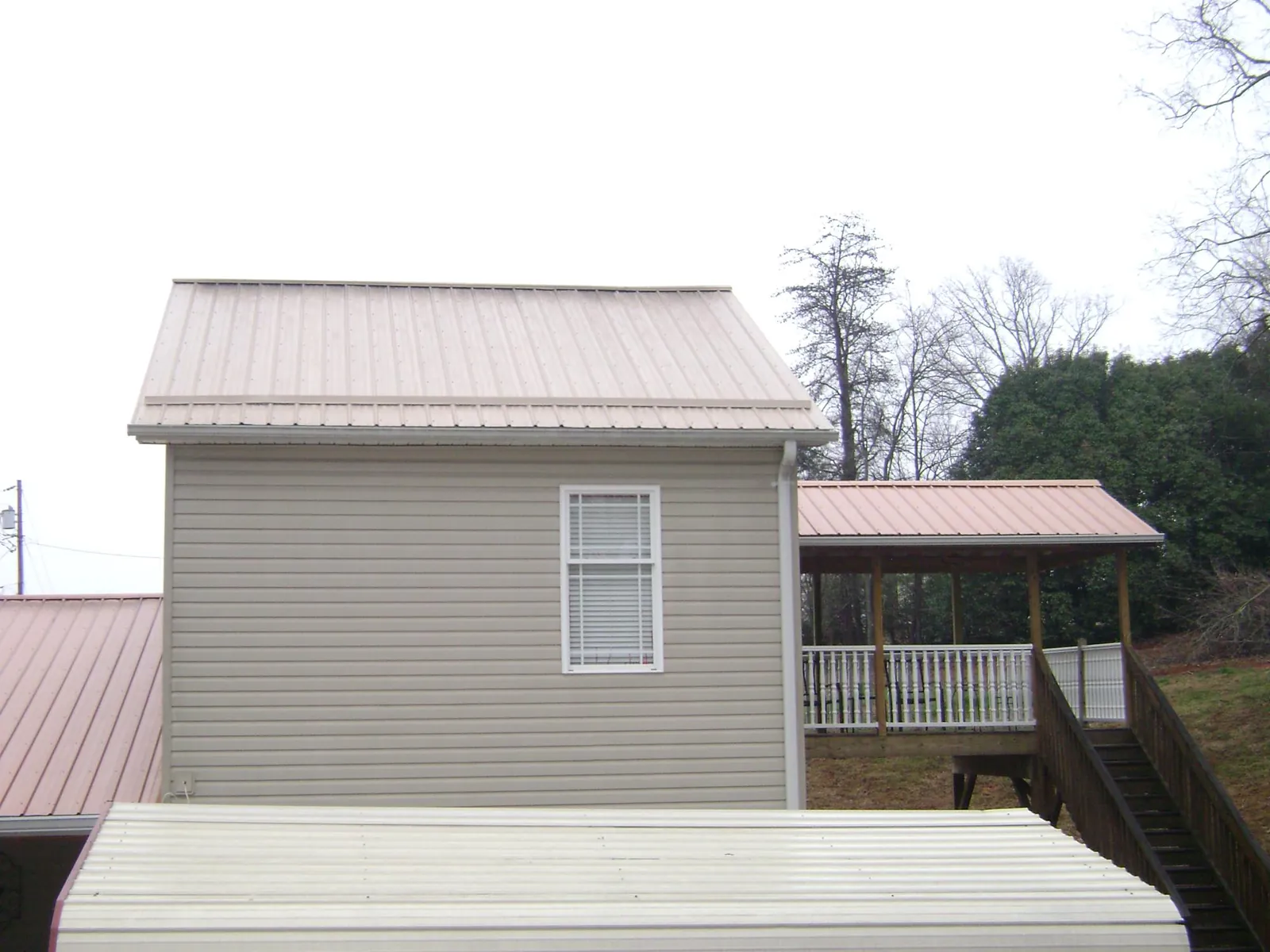 Tan metal roofs on a two story addition and attached porch, from a Roof Replacement job in Ennice