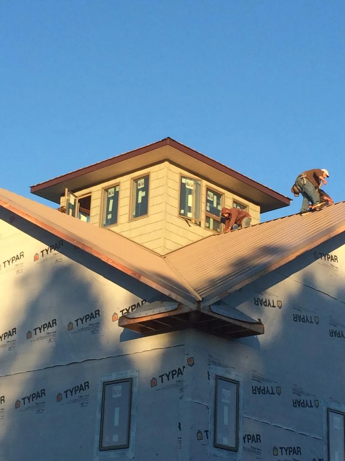 Roofers working around a rooftop cupola on a new metal roof at sunset — Roof Waterproofing in Ennice by Roofing Brothers